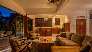 A modern living area with a wooden coffee table, a sofa, and a dining area with a bar. - Nowhere Villa (Pecatu)