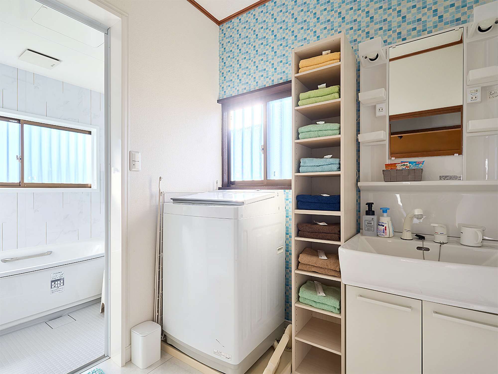 Eine kleine Küche mit integriertem Kühlschrank, Spüle und Fenster.