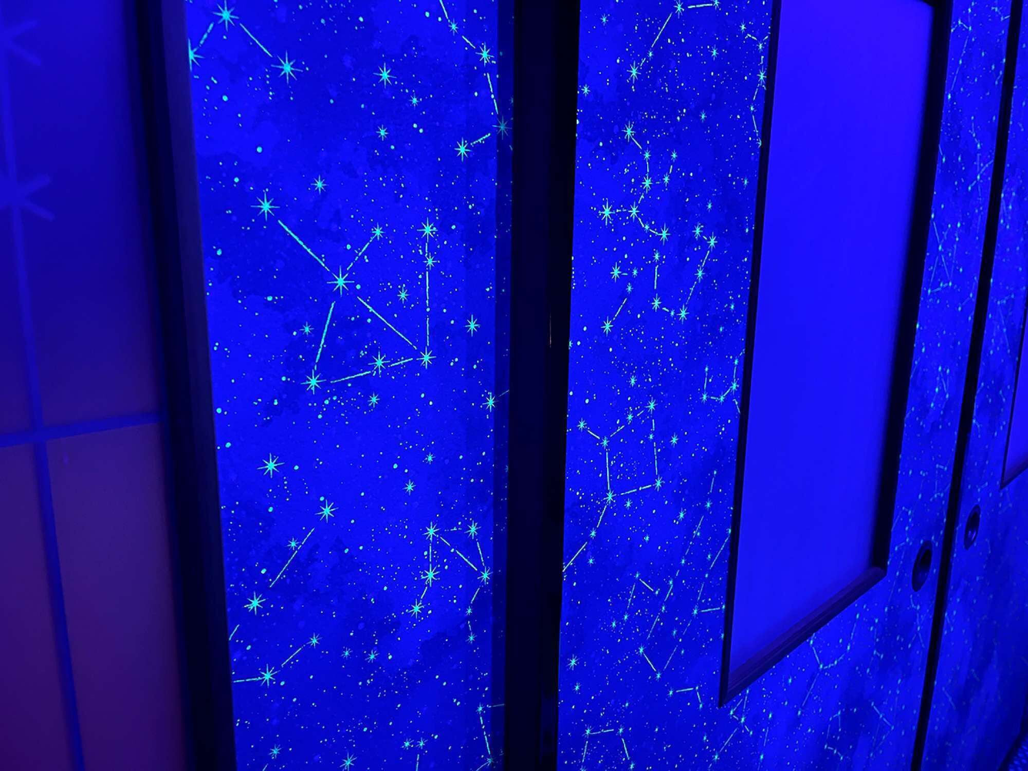 Una habitación con proyección de cielo estrellado en la pared.