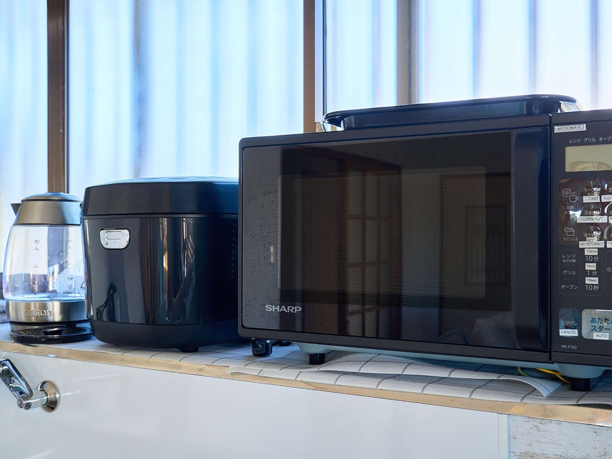 A kitchen with a microwave, a coffee maker, and a kettle on the countertop.