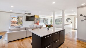 Una cucina moderna con una grande isola, mobili bianchi e una ventola a soffitto.
