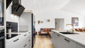 Una cocina moderna con una isla central, horno empotrado y campana extractora de acero inoxidable.
