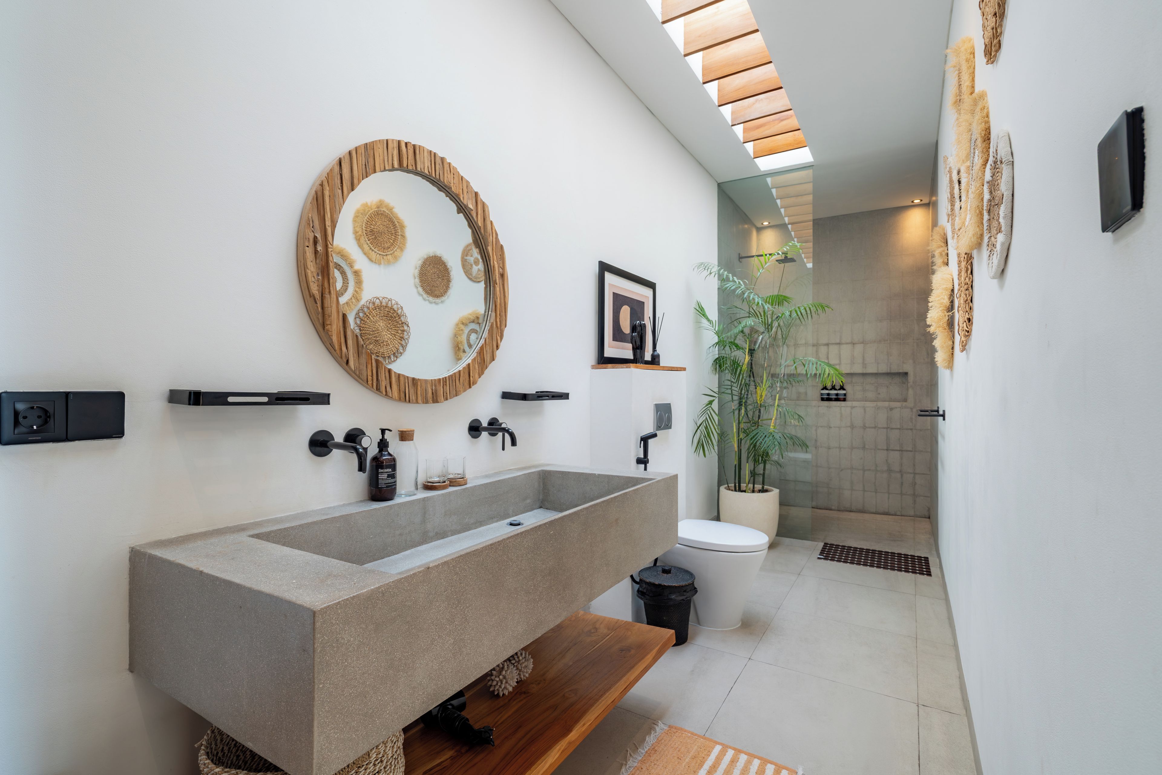 A modern bathroom with a large sink, a mirror, and a shower area.