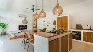 Uma cozinha moderna com ilha central, armários de madeira e iluminação pendente.