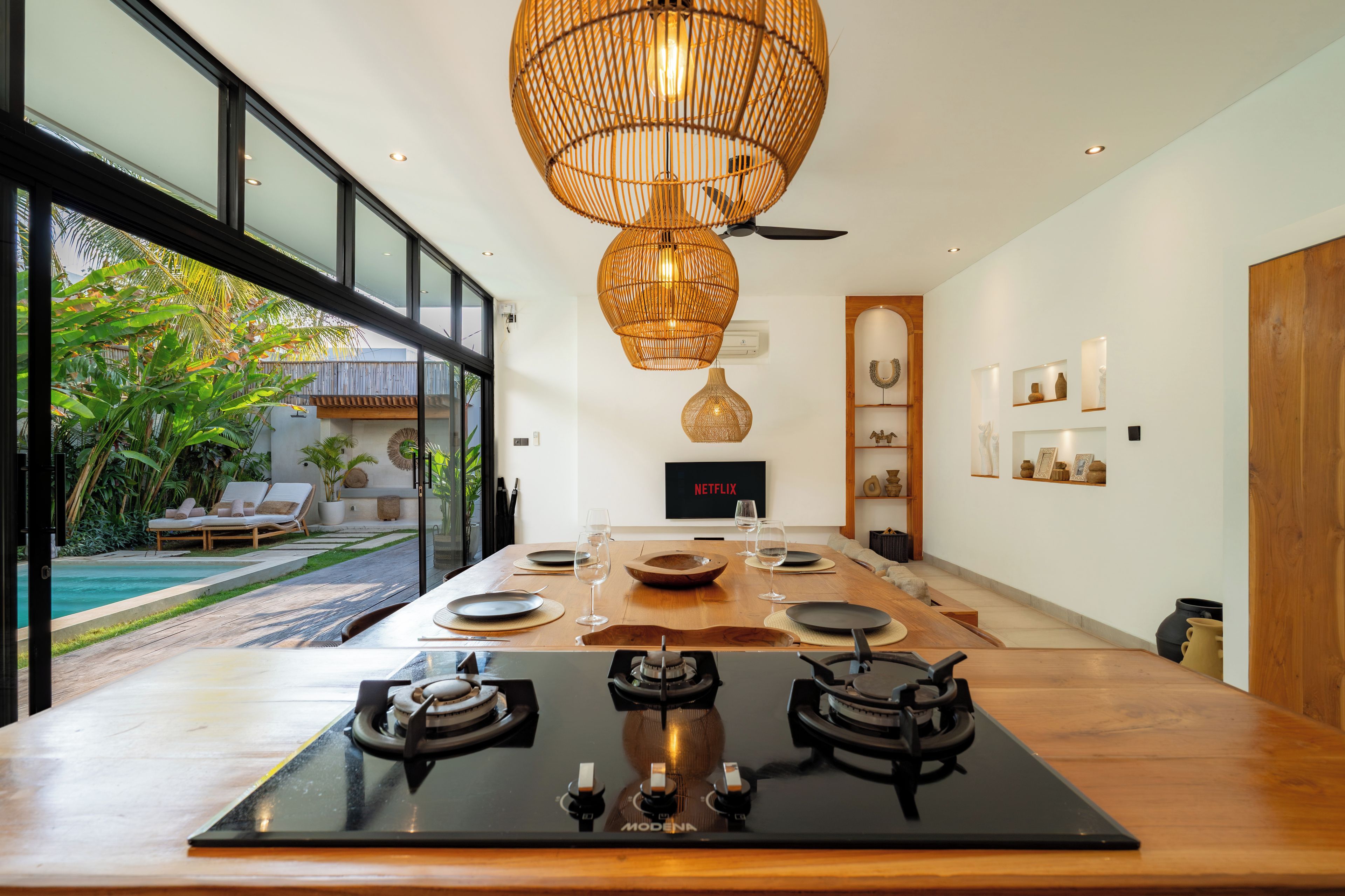 Una cocina moderna con una isla grande, un comedor y vistas a una piscina y jardín.