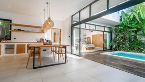 Cozinha moderna com área de refeições, porta de vidro que dá para um quarto e vista para a piscina.