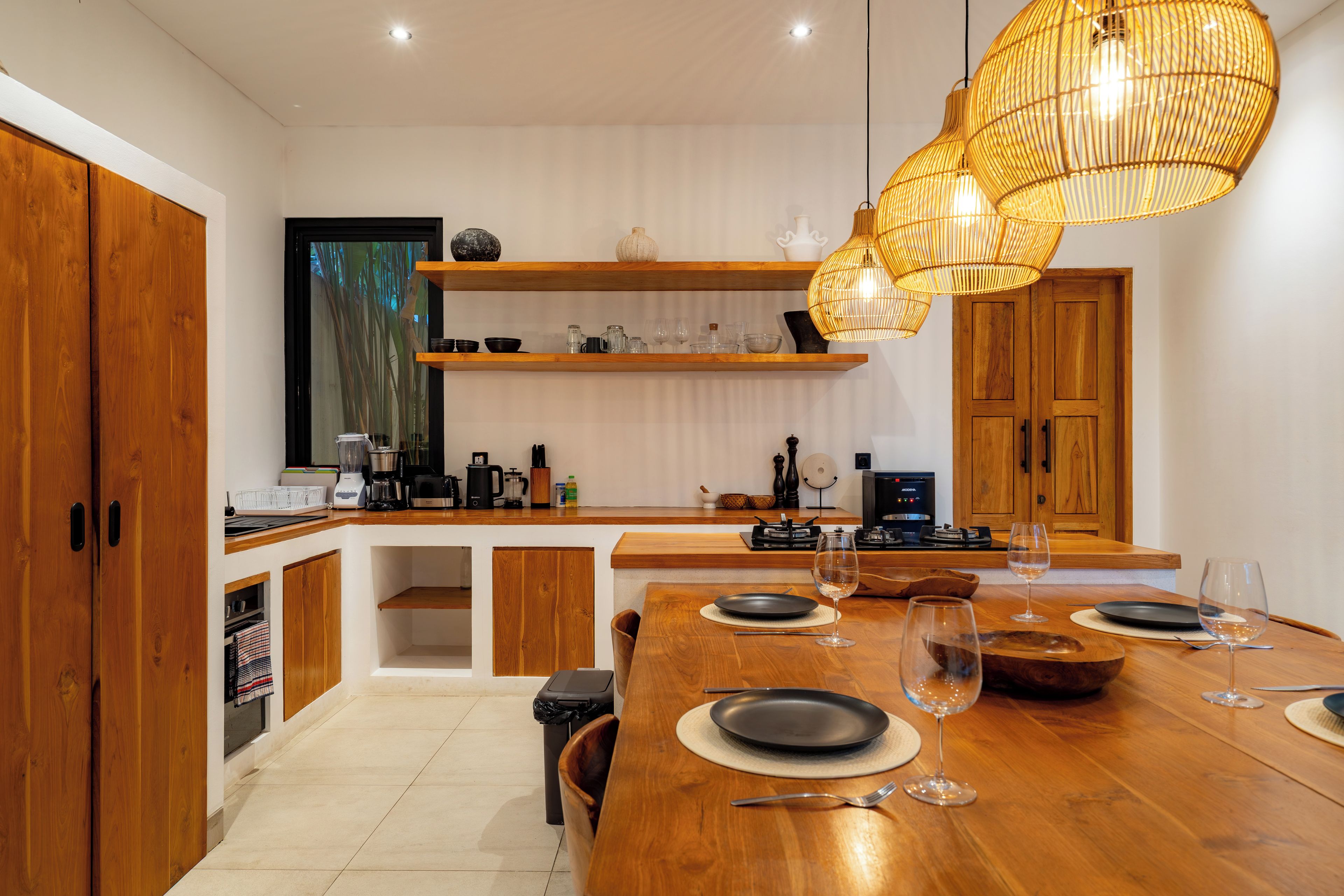 A modern kitchen with wooden cabinets, a dining table set for four, and a hanging light fixture.