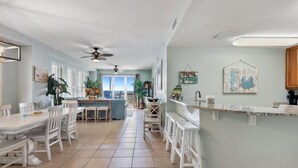 A spacious kitchen with white cabinetry, a central island, and a view to the dining area. - Seychelles 101 (Panama City Beach)