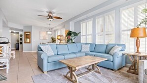 A living room with a light blue sectional sofa, a wooden coffee table, and a ceiling fan. - Seychelles 101 (Panama City Beach)