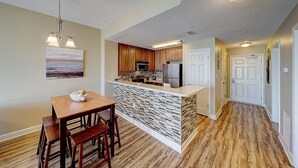 A modern kitchen with wooden cabinets, a central island, and a dining area with a bench. - Seychelles 205 (Panama City Beach)