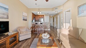 A spacious living room with a television, two sofas, a coffee table, and a ceiling fan. - Seychelles 205 (Panama City Beach)