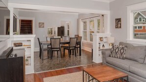 Un salon avec un canapé gris, une table basse en bois et un coin repas comprenant une table et des chaises.