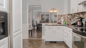 Une cuisine moderne avec des meubles blancs, un pare-feu en carrelage et un îlot central.