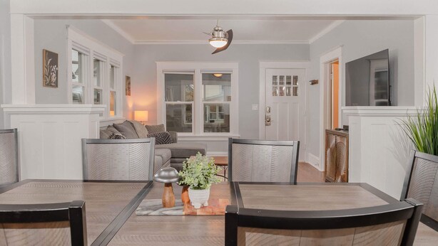 Un coin repas avec une table et des chaises en bois, une plante au centre et un ventilateur de plafond.