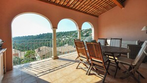 Une terrasse avec une table et des chaises, une vue sur une colline et un sol carrelé.