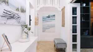 A room with a herringbone floor, a bench, a white door, and a bookshelf. - Glenelg 4BR with pool, 2 min to beach, sleeps 13 (Glenelg South)