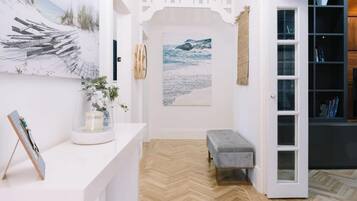 A room with a herringbone floor, a bench, a white door, and a bookshelf.