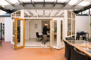 A modern interior with a glass door leading to a dining area.