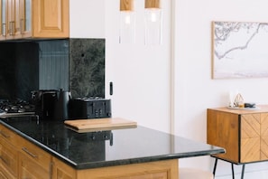 Una cocina moderna con encimera negra, armarios de madera y estufa integrada.
