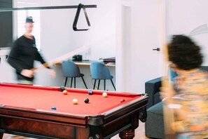 A pool table with balls in a room with modern furniture and a door in the background.