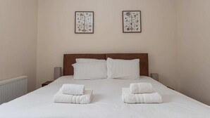 A neatly made bed with white linens and two towels folded at the foot. - Bright & Contemporary 1bedroom Annexe - Herne Hill! (London)