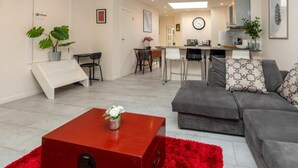 A modern living room with a grey sofa, a red coffee table, and a staircase leading to a second floor. - Bright & Contemporary 1bedroom Annexe - Herne Hill! (London)