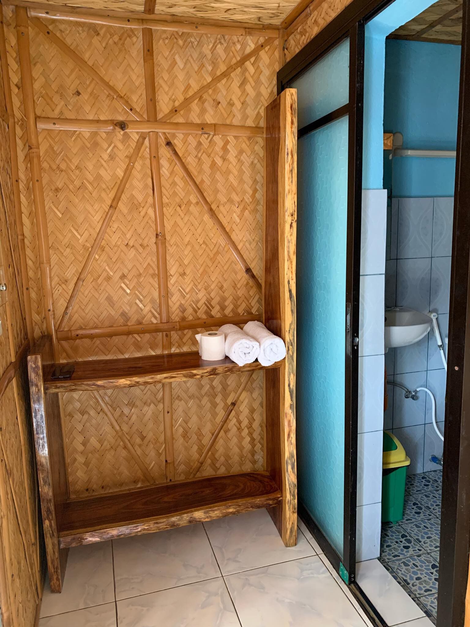 A bathroom with a bamboo wall, a sink, and a toilet.