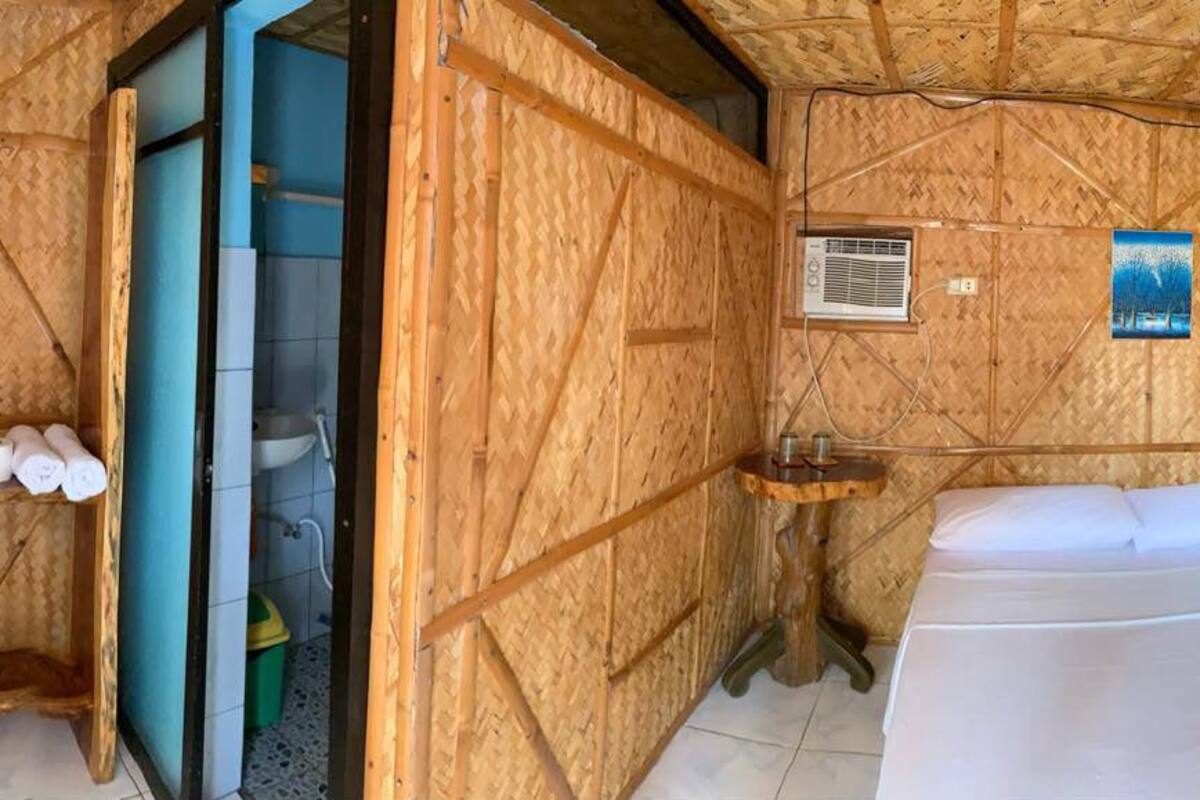 A compact room with a bed, a small sink, and a fan.