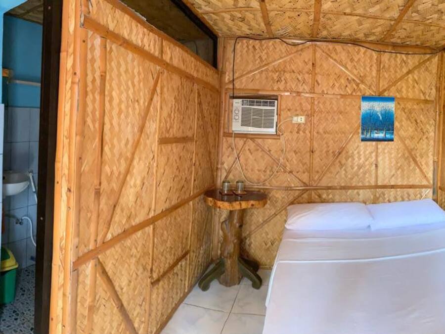 A compact room with a bed, a small sink, and a fan.