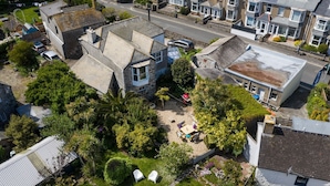 An aerial view of a residential area with houses, a street, and a small garden with outdoor seating. - Ayr Farmhouse (St Ives)