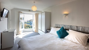 A bedroom with a large bed, a desk, a television, and a window with curtains. - Ayr Farmhouse (St Ives)