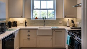 A kitchen with a window, a sink, a stove, and cabinets. - Ayr Farmhouse (St Ives)