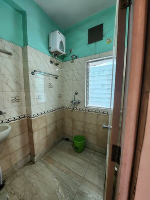 A bathroom with a sink, a green bucket, and a window.