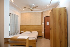 A bedroom with a wooden bed, a ceiling fan, a wooden wardrobe, and a small bedside table.