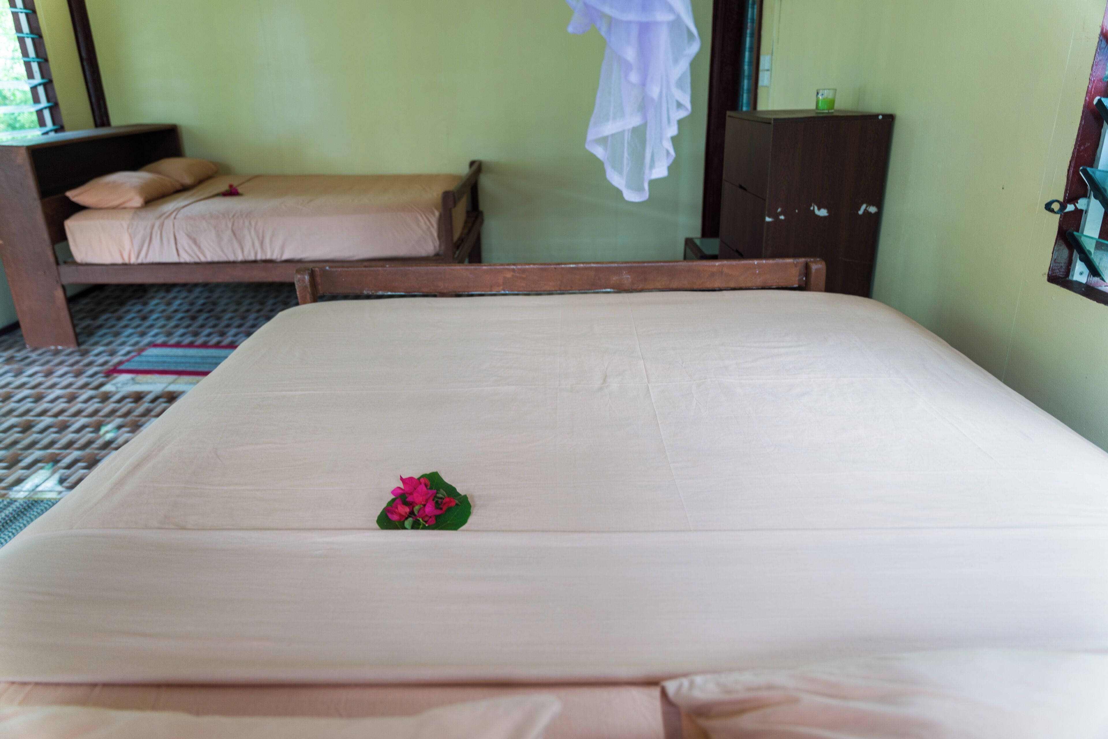 A hotel room with two single beds, a wooden wardrobe, and a window with a curtain.