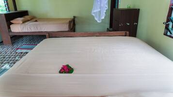 A hotel room with two single beds, a wooden wardrobe, and a window with a curtain.