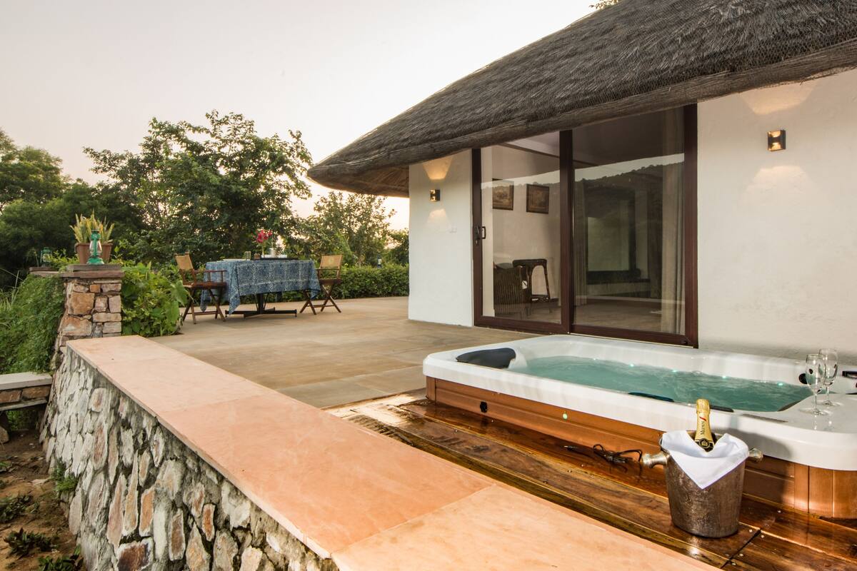 Un área de spa con un jacuzzi, pared de piedra y una mesa con sillas.