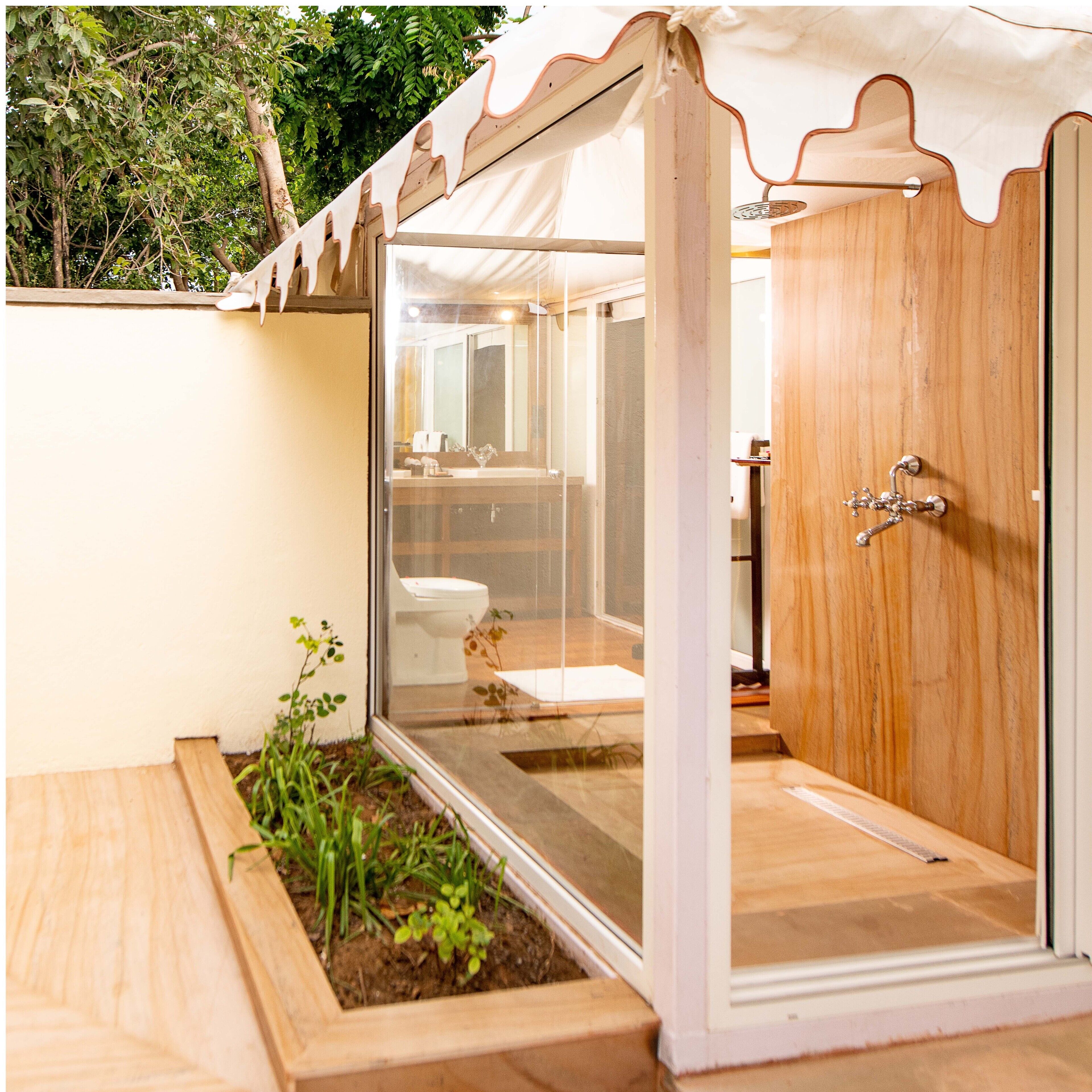 A modern bathroom with a glass shower enclosure, wooden flooring, and a small garden area.