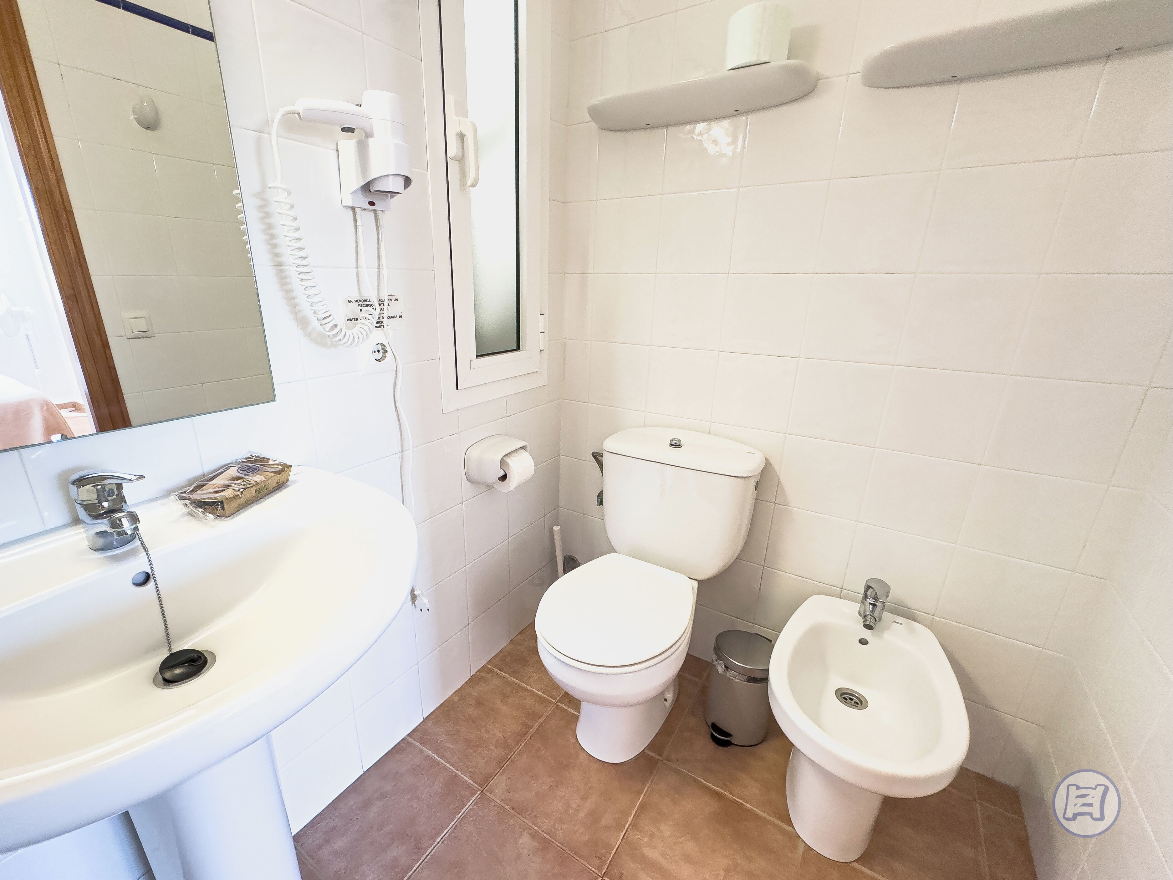 A bathroom with a white sink, toilet, bidet, and a mirror.