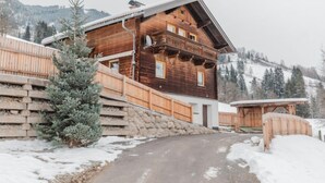 A wooden chalet with a stone retaining wall, a wooden deck, and a view of snow-covered mountains. - beim Kainzbauer by Interhome (Sankt Veit im Pongau)