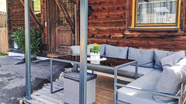 A wooden cabin with a covered porch, a sofa, and a table. - beim Kainzbauer by Interhome (Sankt Veit im Pongau)