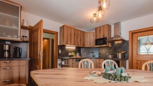 A modern kitchen with wooden cabinets, a large island, and a dining area with chairs. - beim Kainzbauer by Interhome (Sankt Veit im Pongau)