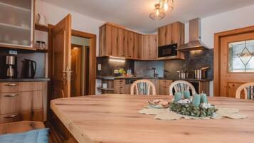 Een moderne keuken met houten kastjes, een groot kookeiland en een eetgedeelte met stoelen.