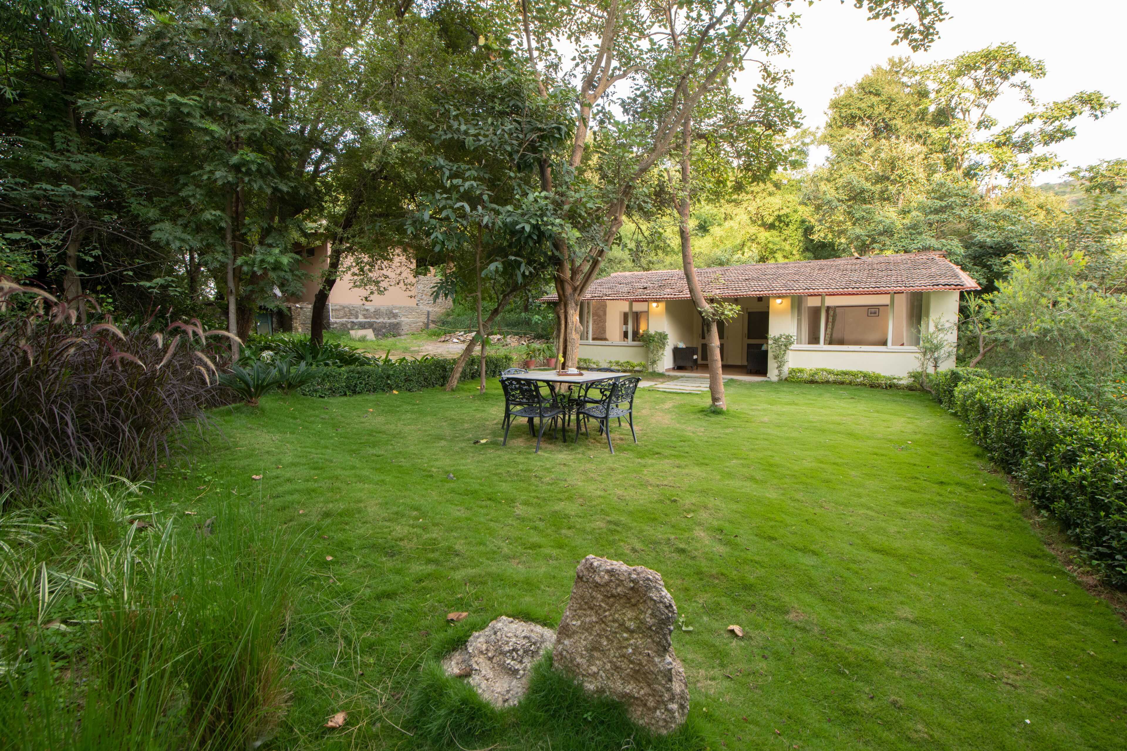 A house with a tiled roof, surrounded by lush greenery and a well-maintained lawn.