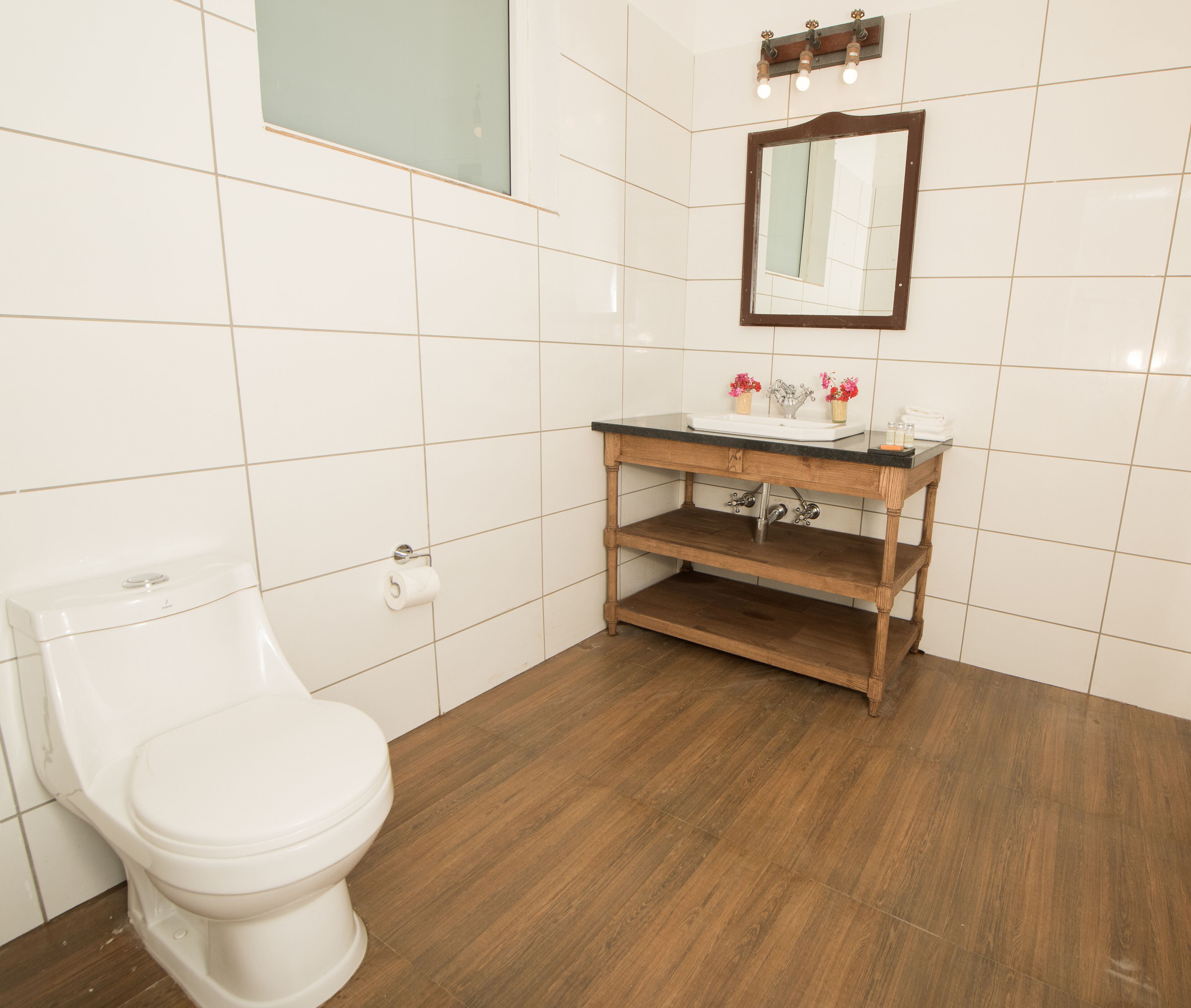A bathroom with a toilet, a wooden vanity with a sink, and a mirror.