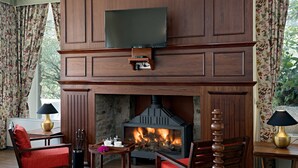 Una sala de estar acogedora con chimenea, muebles de madera y un televisor de pantalla plana montado encima.
