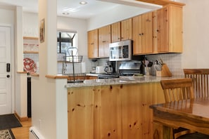 A kitchen with wooden cabinets, a stainless steel refrigerator, and a granite countertop. - West Vail Ptarmigan Townhome - Hot Tub & Easy Bus (Vail)