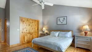 Ein Schlafzimmer mit einem Bett, einem Holzschrank, Nachttischen und einem Deckenventilator.
