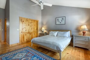 A bedroom with a bed, wooden wardrobe, bedside tables, and a ceiling fan. - Large East Vail Home - Steps to Bus & Gore Creek (Vail)