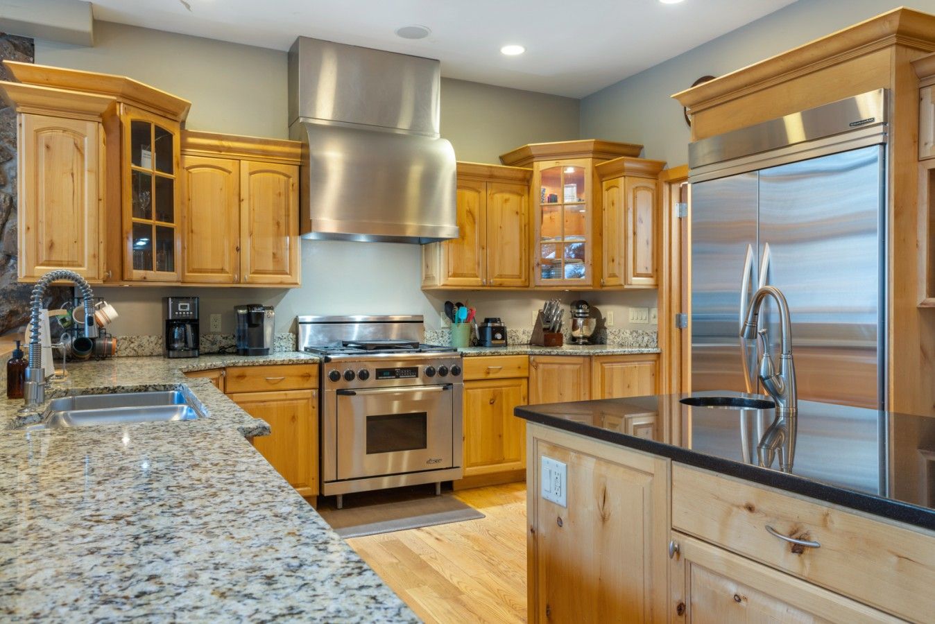 A kitchen with wooden cabinets, stainless steel appliances, granite countertops, and a built-in oven.